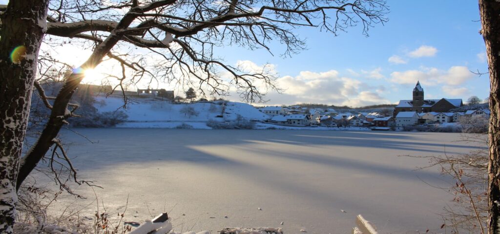Ulmener Maar im Winter mit Blick auf Ulmen, Burgruine und Kirche