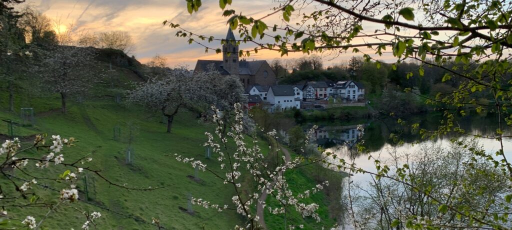 Ulmener Maar im Frühling mit Blick auf Ulmen, Burg und Kirche